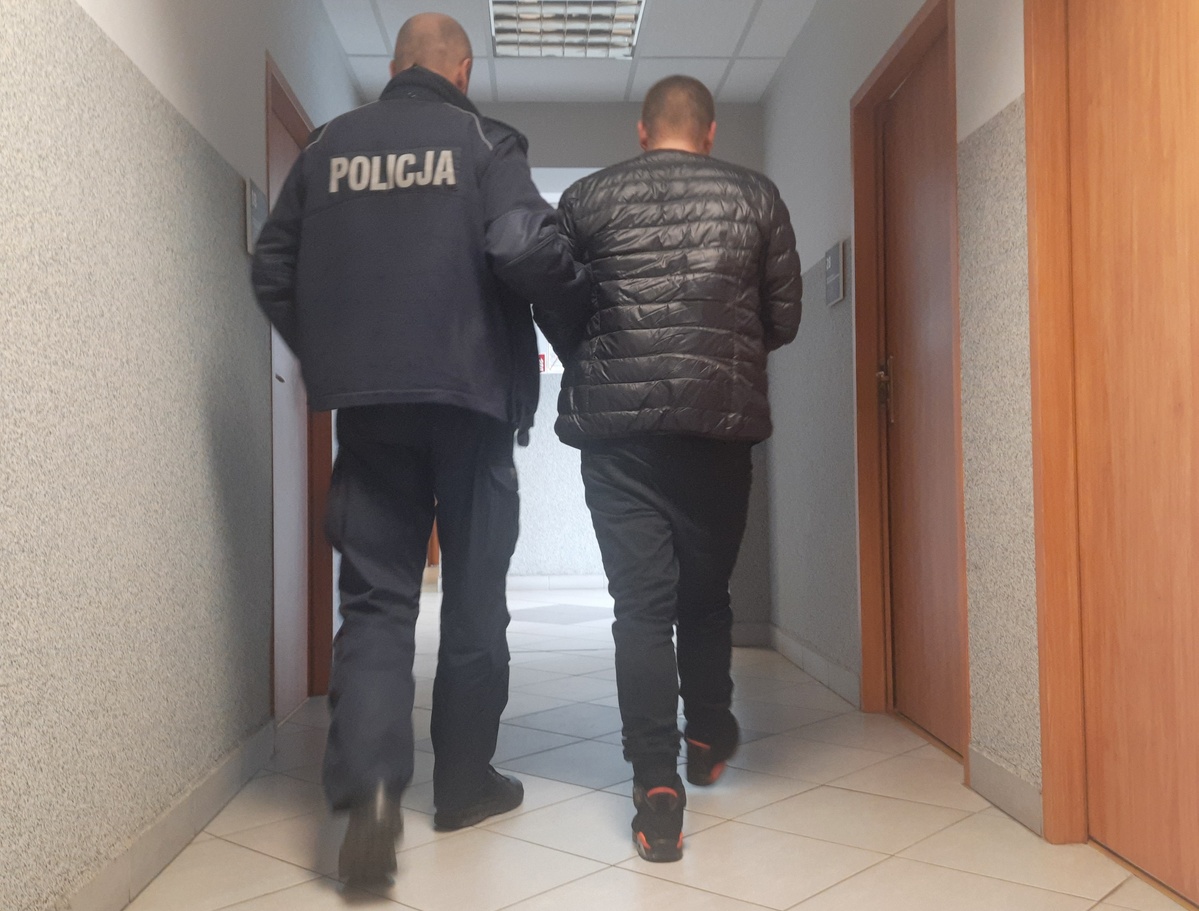 Policjant doprowadza zatrzymanego