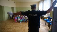 Policjant przedstawia dzieciom na czym polega regulacja ruchem