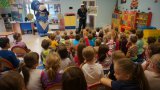 Policjant w towarzystwie Sznupka prowadzi prelekcję z przedszkolakami