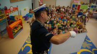 Policjant z dziećmi prowadzi zajęcia o bezpieczeństwie