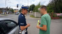 Policjant przekazuje element odblaskowy pieszemu