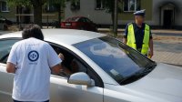 Policjant myszkowskiej drogówki wspólnie z wolontariuszką Fundacji PZU rozdają serduszka z logo kampanii: Kochasz? Powiedz STOP Wariatom Drogowym&quot;