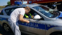 Policjant w radiowozie pisze mandat karny