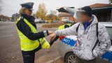 Policjantka wręcza elementy odblaskowe