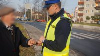 Policjant wręcza opaskę odblaskową