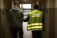 Policjant doprowadza zatrzymanego
