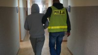 Policjant doprowadza zatrzymanego