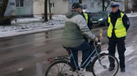 Policjanci wręczają rowerzyście opaskę odblaskową