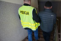 Policjant doprowadza zatrzymanego