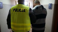 Policjant doprowadza zatrzymanego