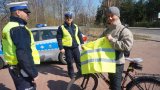 Policjanci wręczają kamizelki odblaskowe