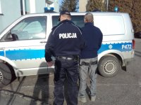 Policjant doprowadza zatrzymanego