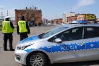 Policjanci patrolują plac dworcowy przed radiowozem