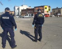 Policjant i strażnik kontrolują plac dworcowy