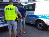 Policjant doprowadza zatrzymanego