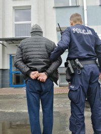 Policjant doprowadza zatrzymanego