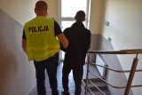 Policjant w kamizelce z napisem Policja doprowadza zatrzymanego po schodach