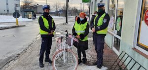 Policjanci z rowerzystką w kamizelkach odblaskowych pozują do zdjęcia