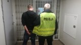 Policjant doprowadza zatrzymanego