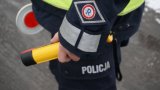 Policjant trzyma w ręku alkotest i tarcze do zatrzymywania pojazdów