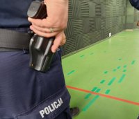 Policjant trzyma rękę na broni, która jest w kaburze