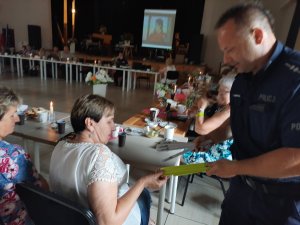 Policjant wręcza opaski odblaskowe