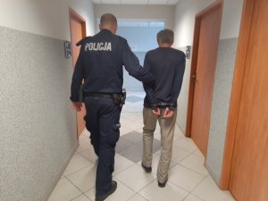 Policjant doprowadza zatrzymanego