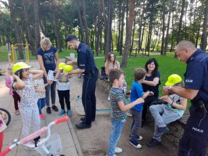 Policjanci wręczają dzieciom czapki