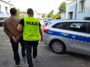 Policjant doprowadza zatrzymanego