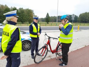 Policjanci rozmawiają z rowerzystą- w tle radiowóz