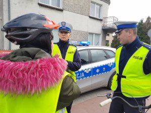 Policjanci rozmawiają z kobietą która ma na głowie kask ochronny