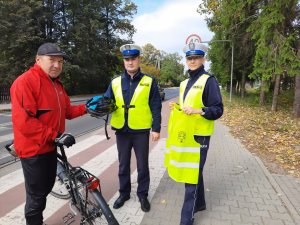 Policjant wręcza kask rowerzyście