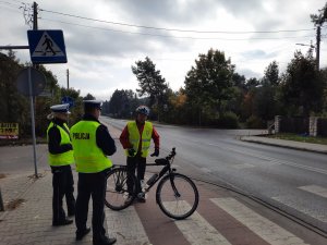 Policjanci rozmawiają z mężczyzną, który stoi z rowerem