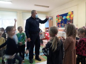 Policjant gestykuluje wśród dzieci