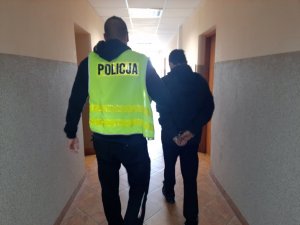 Policjant doprowadza zatrzymanego