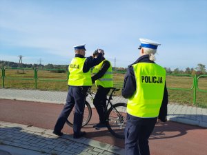 Policjant zakłada kask ochronny na głowę rowerzysty