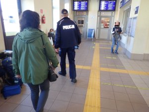 Policjant i kobieta kontrolują dworzec kolejowy