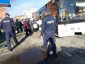 Policjanci kontrolują pasażerów wsiadających do autobusu