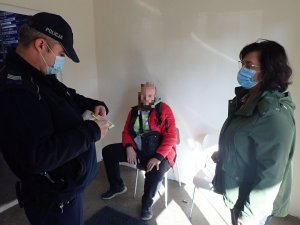 Policjant i kobieta rozmawiają z mężczyzną, który nie ma maseczki