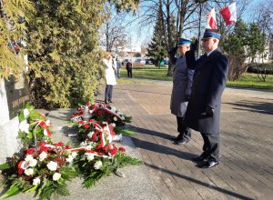 Policjant i strażak pod pomnikiem oddają honor poległym