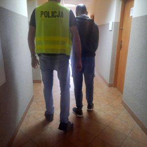 Policjant doprowadza zatrzymanego