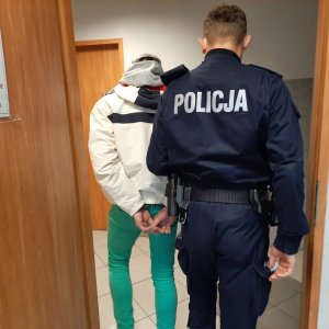 Policjant doprowadza zatrzymanego