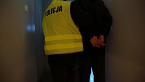 Policjant doprowadza zatrzymanego