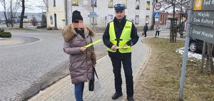 Policjant wręcza opaskę odblaskowa pieszej