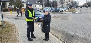 Policjant przekazuje  odblask pieszej