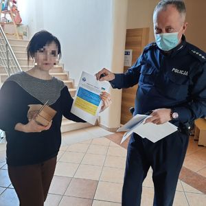 Policjant wręcza ulotkę kobiecie