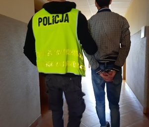 Policjant doprowadza zatrzymanego