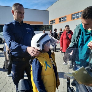 Policjant zakłada dziecku policyjny hełm na głowę