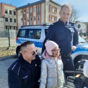 Dziewczynka pozuje do zdjęcia z policjantami