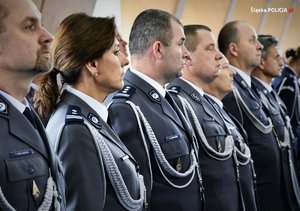 Komendanci i oficerowie stoją w hali podczas ślubowania nowych policjantów